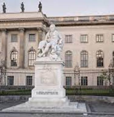 A statue sits in the middle of a square surrounded by buildings at Humbolt Universität zu Berlin