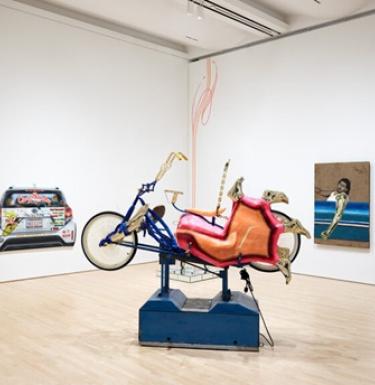 An artistic representation of a lowrider bicycle displayed in a gallery.